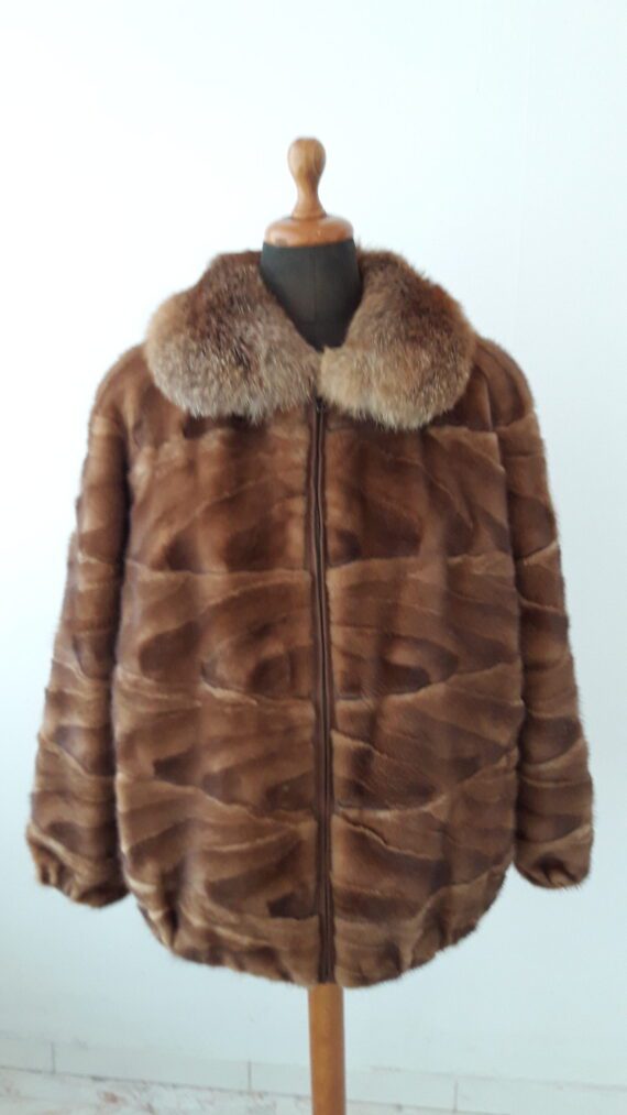 a white section mink jacket with a stand collar and a hook and eye closure