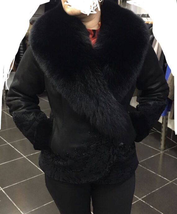 A woman wearing a black sheepskin coat with black fox fur trim and a black hat.