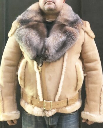 A brown sheepskin biker jacket with a detachable crystal fox fur collar, standing in front of a white wall. The jacket has a zip front closure, two zip pockets, and a belt at the waist.