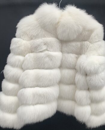 A woman wearing a white fox fur jacket with a hook and eye closure and pockets.