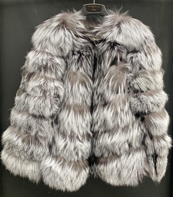 A woman wearing a silver fox fur jacket with a hook and eye closure and pockets.