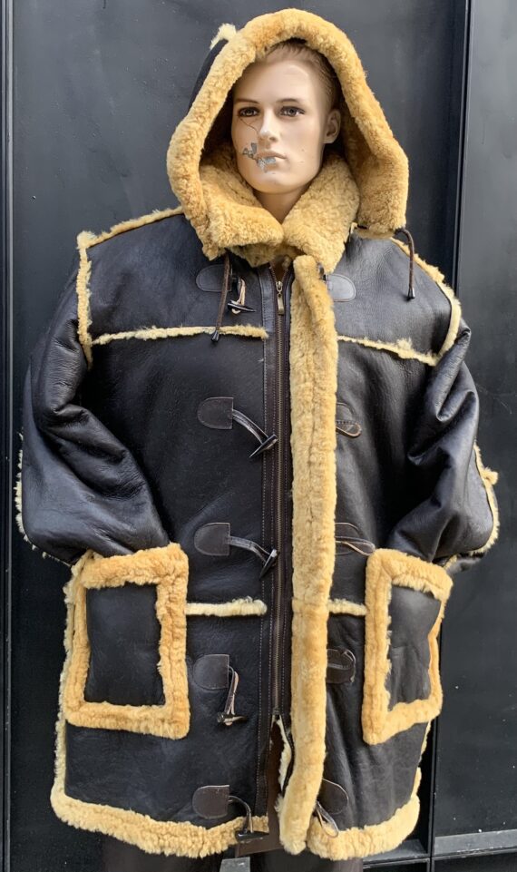 A man wearing a brown Shearling 7/8 coat with a gold zipper and a hood.