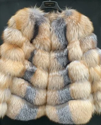 A woman wearing a silver fox fur jacket with a hook and eye closure and pockets.